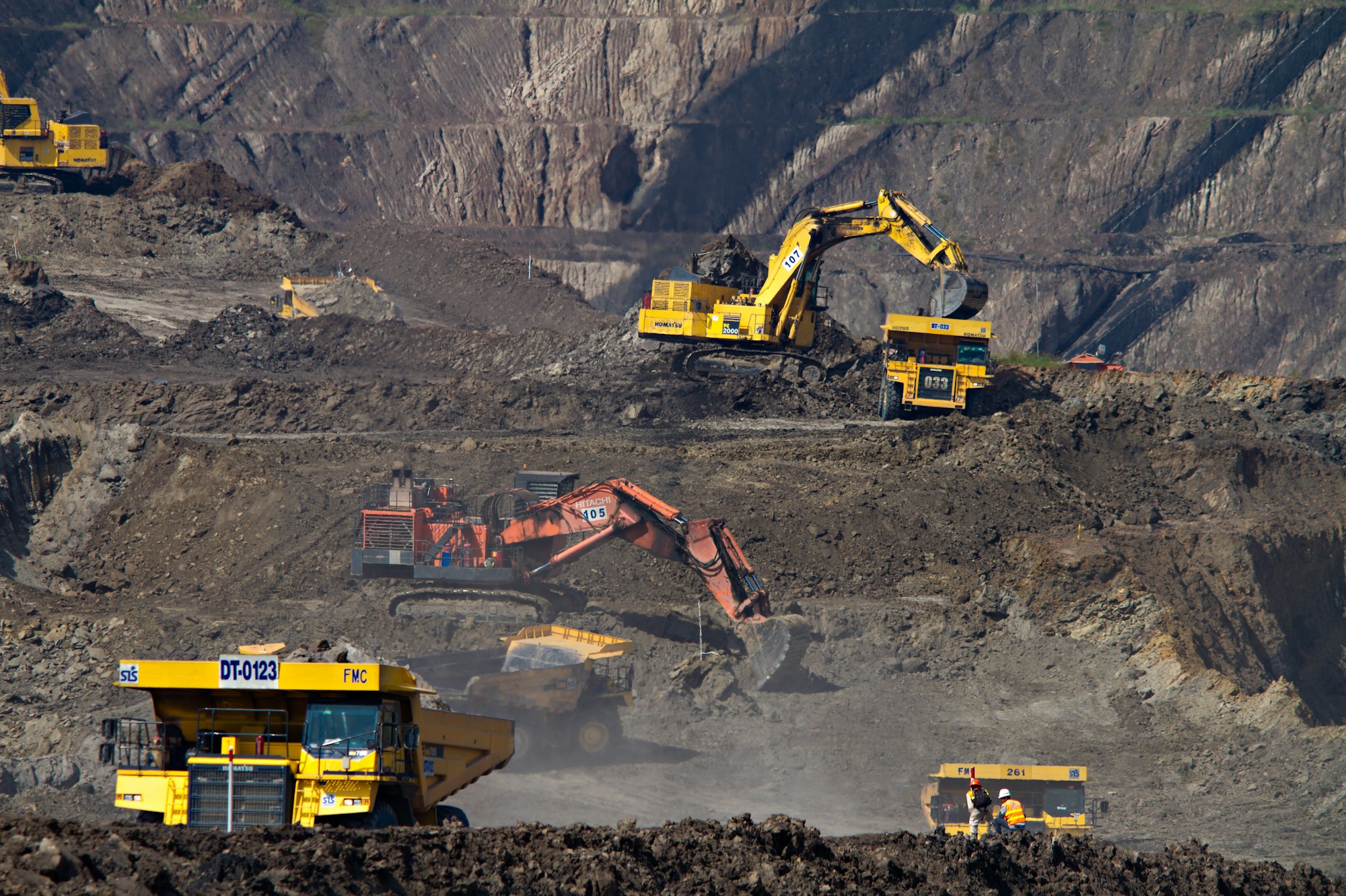 Active quarry with excavators and haul trucks at an open-pit drill and blast operation